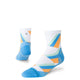 To blå Stance Gamma Ray UL Quarter unisex-strømper: en opretstående og fremadrettet, den anden viser hælen og siden. Begge har geometriske blå, orange og grønne mønstre med kontrastfarvede tæer.