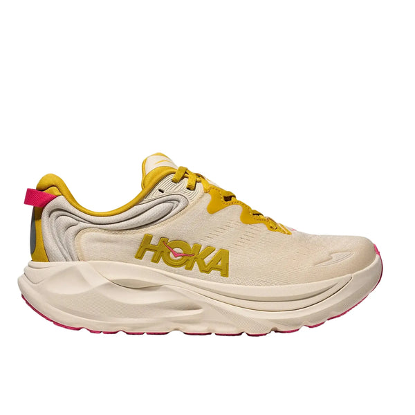 Hoka Gaviota 6 Dame i Birch/Yellow Gold har en beige overdel med gule detaljer, pink ydersål, fedt Hoka-logo på siden, tyk, skulpturel sål og et lavt snit.