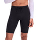 Der vises en person fra underkroppen til lårene, iført sorte, tætsiddende løbeshorts – nærmere bestemt modellen »On Zero Half Tight, Herre«. Disse shorts har et tætsiddende design med snøre i taljen og er kombineret med en hvid, langærmet, kort top, alt sammen på en ensfarvet baggrund.