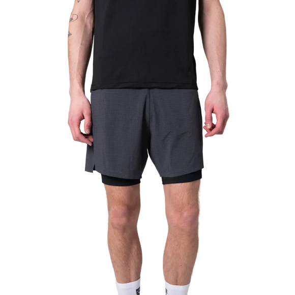 En person iført sort t-shirt, Liiteguard Glu-Tech Running 2In1 Shorts for men i ibenholt og hvide strømper står på en almindelig hvid baggrund.