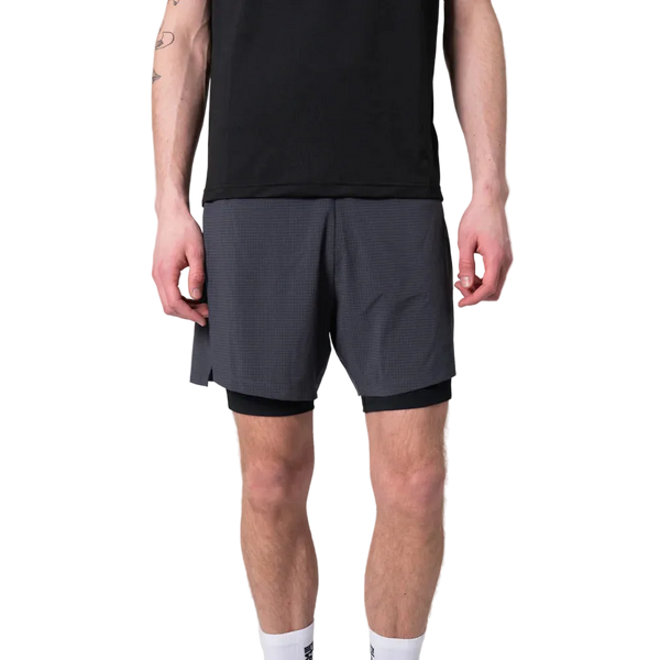 En person iført sort t-shirt, Liiteguard Glu-Tech Running 2In1 Shorts for men i ibenholt og hvide strømper står på en almindelig hvid baggrund.
