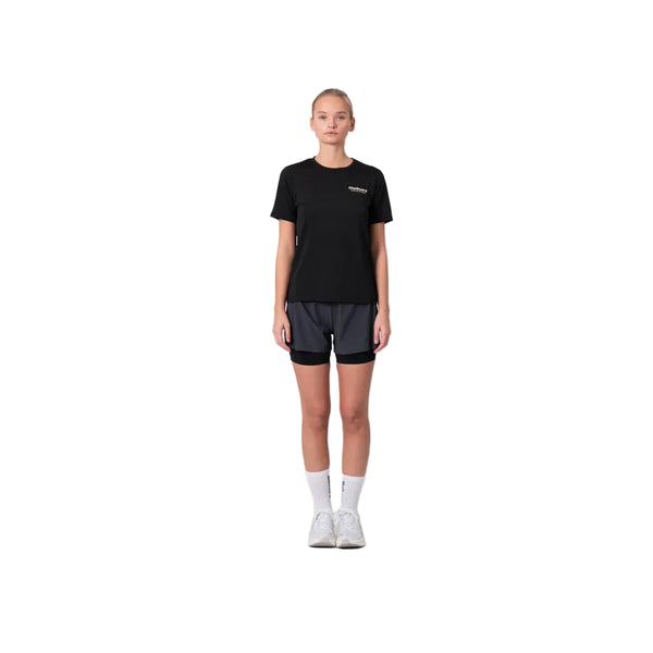 En person står med ansigtet vendt fremad, iført en sort T-shirt, hvide sokker og hvide sneakers, og har Liiteguard Glu-Tech Running 2-i-1-shorts til kvinder i farven Ebony på, foran en ensfarvet hvid baggrund.