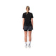 En person med blondt hår i en hestehale står med ryggen til kameraet iført en sort T-shirt, Liiteguard Glu-Tech Running 2-i-1-shorts til kvinder i farven Ebony, hvide sokker og hvide sneakers foran en ensfarvet hvid baggrund.