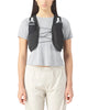 Der vises et billede af en person fra livet og opefter, der står med ansigtet fremad, iført en lysegrå T-shirt med korte ærmer og beige bukser samt et sort Salomon Gravel Skin 4-sæt (unisex) med to synlige vandflaskelommer på brystet.