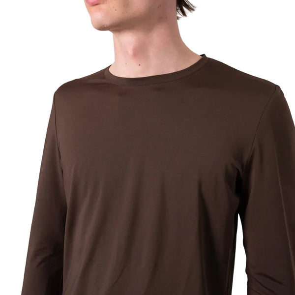 Et billede viser en person, der bærer en ensfarvet brun Liiteguard Ground-Tech Light LS T-shirt til mænd i farven Coffee Bean, fremstillet af det innovative S.Café®-materiale, set fra skuldrene til hagen på en hvid baggrund. Personens ansigt er delvist uden for billedet, hvilket fremhæver denne alsidige løbetrøje til mænd.