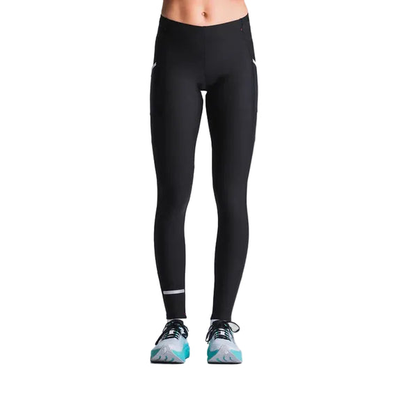 En person bærer Fusion Hot Long Tights, Unisex, Black, sammen med blågrønne løbesko. Billedet viser underkroppen og benene mod en almindelig lys baggrund.