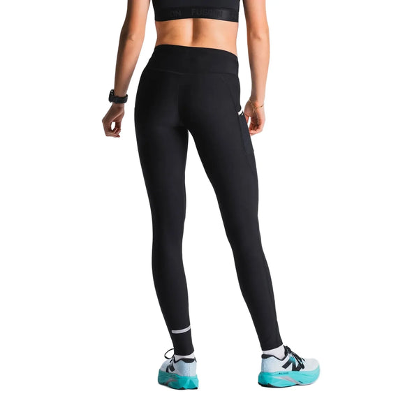 En person står på en hvid baggrund, set bagfra, iført en sort sports-bh, et ur, blågrønne sportssko med sorte og hvide detaljer og Fusion Hot X-Long Tights i sort (unisex).