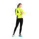På en almindelig baggrund står en person iført Fusion's Hot X-Long Tights i sort og kigger ned på sit håndled, som om han tjekker et ur eller en fitness-tracker.