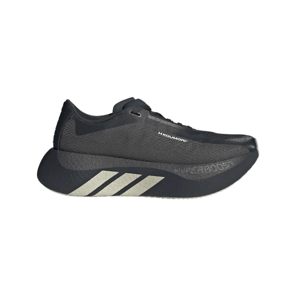 Adidas Hyperboost Edge i farvekombinationen Chacoa/Ntgrey/Alumin x Hermanos Koumori er en sort løbesko til kvinder med en tyk sål, diskret logo på siden og tre diagonale sølvstriber nær hælen. Denne komfortfokuserede løbesko til landevejsløb, der vises på en hvid baggrund, kombinerer stilfuldt design med enestående komfort til din løbetur.