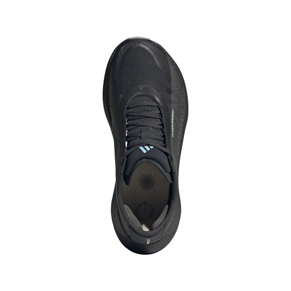 Et billede set ovenfra af Adidas Hyperboost Edge Dame-løbeskoen i farvekombinationen Chacoa/Ntgrey/Alumin x Hermanos Koumori, der viser en sort løbesko med en overdel i struktureret mesh, sorte snørebånd og diskrete mærkedetaljer, såsom et lille logo tæt på tungen. Dette minimalistiske, strømlinede design lægger vægt på komfortorienteret vejløb.