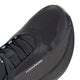 Nærbillede af fronten og siden af en sort sportssko med teksten »H. KOUMORI« trykt i hvidt på ydersiden. Skoen er designet som en komfortfokuseret løbesko til landevejsløb og har en overdel i mesh samt sorte snørebånd, der minder om den avancerede teknik, man finder i Adidas’ Hyperboost Edge, Dame, Chacoa/Ntgrey/Alumin x Hermanos Koumori.