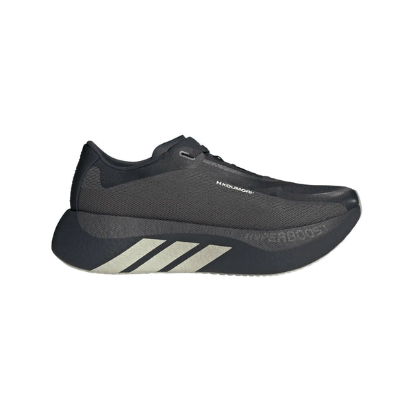 En Chacoa/Ntgrey/Alumin Hyperboost Edge herre-løbesko fra Adidas x Hermanos Koumori med tre lyse striber på siden, en tyk sål og teksten »HYPERBOOST«, der delvist kan ses nær tåen, fotograferet på en hvid baggrund. Denne komfortfokuserede herreløbesko er designet til optimal komfort og ydeevne.