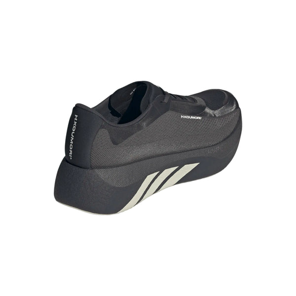 Adidas Hyperboost Edge i farvekombinationen Chacoa/Ntgrey/Alumin x Hermanos Koumori er en løbesko til mænd, der har et sort design med en tyk, buet sål og markante hvide diagonale striber på siden. ”HIKOMORI” er trykt tæt på hælen, hvilket understreger, at skoen er designet med fokus på komfort til vejløb. Herreskoen præsenteres på en ensfarvet hvid baggrund.