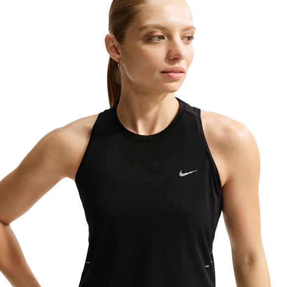 En kvinde med lys hud og glat brunt hår i hestehale bærer en sort Nike Nk Swift Nvlt Brthe Tank til kvinder med hvide og reflekterende sølvdetaljer og ser lidt til venstre mod en hvid baggrund.