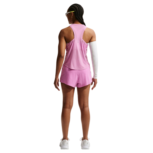 En person med flettet hår står med ryggen til og er iført en Nike Nk Swift Nvlt Brthe Tank og matchende shorts i Lt Magenta/Photon Dust/Reflective Silv, hvide sneakers og et hvidt ærme på højre arm. Baggrunden er almindelig hvid.