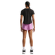 En person med flettet hestehale, klædt i sort t-shirt, Nike Swift Breathe Mid-Rise 2.5" løbeshorts til kvinder i Lt Magenta/Photon Dust/Reflective Silver, hvide sokker og sort-hvide sneakers står med ansigtet vendt væk.