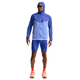 En mand iført blå jakke med hætte, orange sokker, lysorange løbesko, solbriller og Nike Stride Running Half Tights Herre i Lapis/Reflective Silv (med Dri-FIT-teknologi) står med front mod en almindelig hvid baggrund.