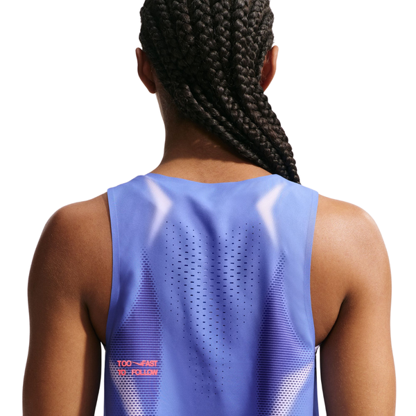 En person med langt flettet hår, set bagfra, er iført en ærmeløs Nike Nk Arswft Dfadv Crop Tank Gx i Sapphire/Hot Lava med ventilationshuller og lille rød tekst nederst til venstre på en hvid baggrund.