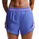 En kvinde står med hænderne på hofterne iført Nike Nk Arswft Dfadv 3In Short Gx dame løbeshorts i Sapphire/Hot Lava med et lyserødt Nike-logo på en almindelig hvid baggrund, der fremhæver deres sporty stil.
