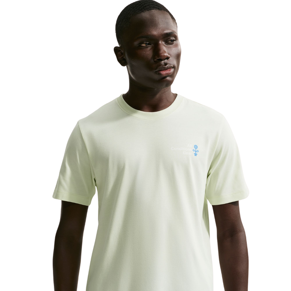 En herre modellerer Nike ACG Dri-FIT T-shirt i Sea Glass med et diskret logo på venstre bryst, mens han står på en hvid baggrund og kigger lidt til siden.