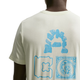En mand bærer en Nike ACG Dri-FIT T-shirt i lyst havglas med tre blå grafikker på ryggen: en stenbue, en rektangulær udskæring og en firkant med et udsmykket cirkulært mønster.