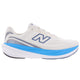 New Balance Infinion 1080 V15, Herre, Angora er en hvid løbesko med en blå stribe på mellemsålen, en tyk, polstret og stødabsorberende sål samt et blåt N-logo på siden. Vist på en ensfarvet hvid baggrund.