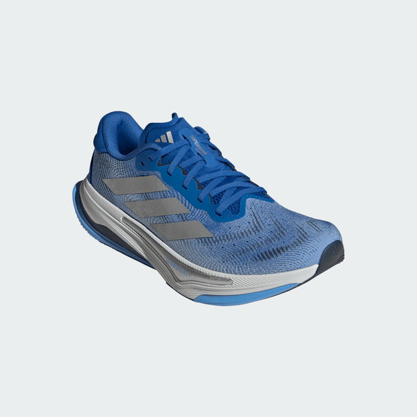 Adidas Supernova Prima 2 Herre i Blue/Silvmt/Blubrs har et komfortorienteret løbesko design, hvid sål, blå snørebånd og Adidas-logo på siden og tungen, der vises mod en lysegrå baggrund.