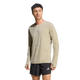 En mand er iført en lys beige Adidas Adi365 Long Sleeve Shirt, Herre, Woca med huller til tommelfingrene og sorte sportsshorts, begge med små Adidas-logoer, på en almindelig hvid baggrund.
