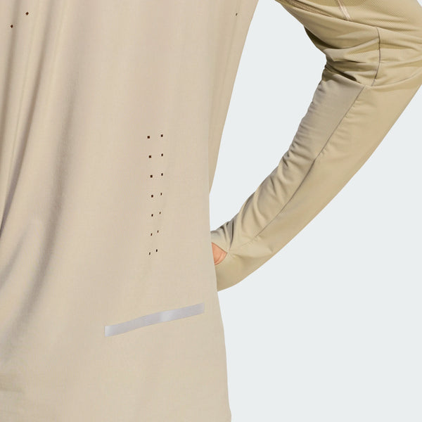 En person ses bagfra iført en Adidas Adi365 Long Sleeve Shirt, Herre, Woca, med små ventilationshuller og en vandret refleksstribe i bunden, med den ene arm bøjet og hånden på hoften.