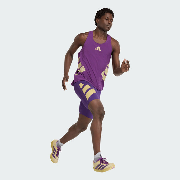 En person løber iført Adidas Rtr Singlet, Herre, Violet, med matchende shorts og løbesko med grå sokker på en almindelig lysegrå baggrund.