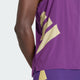 Et nærbillede af en persons ryg iført Adidas Rtr Singlet, Herre, i violet - en ærmeløs atletisk top med gule geometriske mønstre og små perforeringer - sammen med matchende lilla shorts.