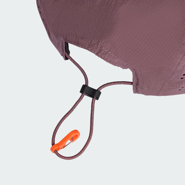 Nærbillede af Adidas Hk Cap (Unisex, Shafig/Refsil) i rødbrunt stof med en løbegang, der er ført gennem en sort snorelås og slutter med en orange plastikkrog. Baggrunden er ensfarvet og lys.