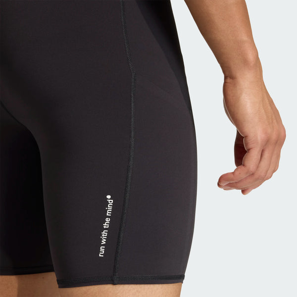 Et nærbillede viser en mands underkrop og overben i Adidas Adi365 Hk Tight, Herre, Black, med hvid "run with the mind"-tekst nær kanten. Hans højre arm ses ved siden af shortsene.