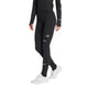 En person iført sorte Adidas Adi365 Climawarm+ løbetights (Dame) med reflekterende detaljer, en sort langærmet trøje og hvide sneakers står foran en ensfarvet hvid baggrund.