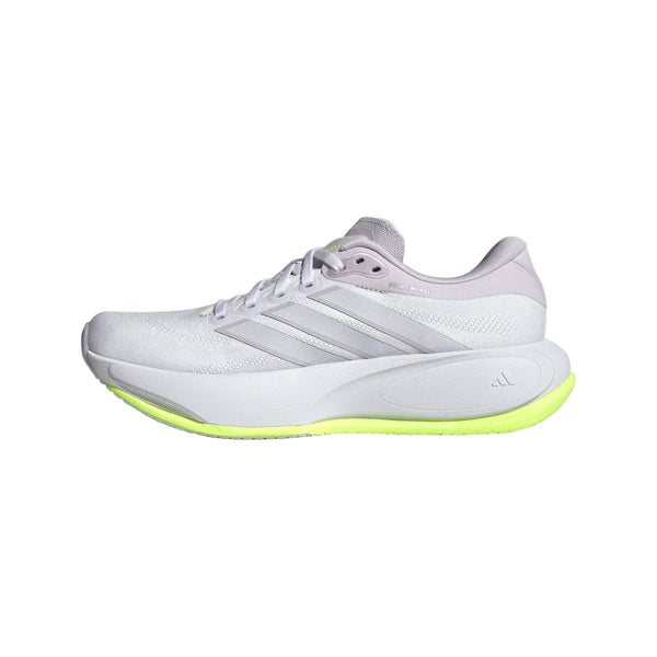 En adidas Supernova Prima 3-løbesko til kvinder i farverne Fropur/Whitin/Hireye ses set fra siden på en hvid baggrund. Den hvide træningssko til daglig løbetræning har lysegrå detaljer og tre karakteristiske striber langs siden samt en kraftig sål med en markant gulgrøn underside, inspireret af det ikoniske Supernova-design.