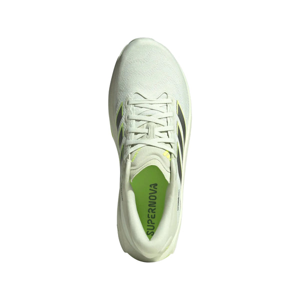 En hvid Adidas Supernova Prima 3 herreløbesko i farvekombinationen Cryjad/Ironmt/Siggnr ses set ovenfra med limegrønne detaljer, karakteristiske sorte sidestriber og ordet »SUPERNOVA« trykt på indersålen. Skoen, der er isoleret på en hvid baggrund, tilbyder blød støddæmpning, der sikrer en behagelig løbeoplevelse.