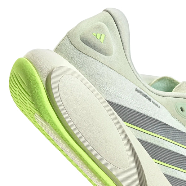 Nærbillede af adidas Supernova Prima 3, herresko i farvekombinationen Cryjad/Ironmt/Siggnr i lysegrøn (cryjad) og hvid med neongrønne detaljer, de karakteristiske grå striber, en struktureret sål og et diskret logo på hælen. Designet kombinerer glatte materialer og mesh for optimal åndbarhed og støtte, hvilket gør den til en fremragende herreløbesko med blød støddæmpning, der sikrer komfort på hver eneste løbetur.