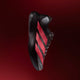 En sort Adizero Evo SL Dame-løbesko fra Adidas med guld- og lyseblå detaljer (Cblack/Soltur/Ltonix) vises i profil mod en mørkerød baggrund med farveovergang. Sneakeren har Adidas-logoet, snørebånd, en struktureret sål og avanceret LIGHTSTRIKE PRO-skumstøddæmpning.