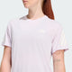 En person med langt rødt hår er iført en Adidas Adi365 Running Tee, Dame, Icelav, med hvide diagonale ærmestriber og et lille logo på brystet. En biltatovering er synlig på højre underarm.