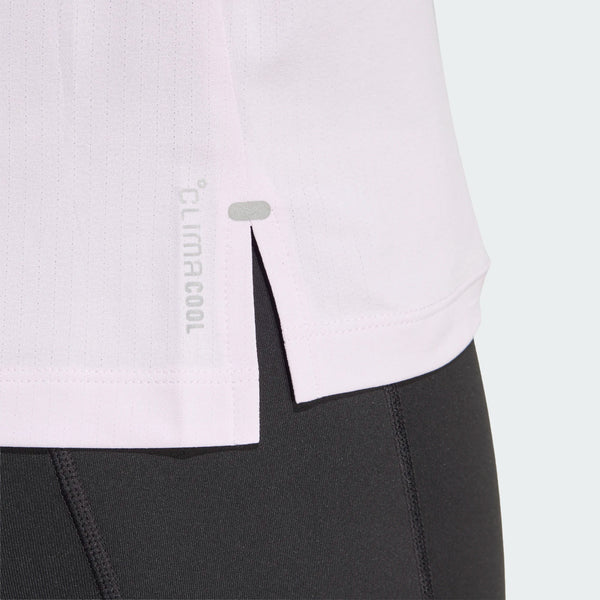 Nærbillede af undersiden af den lyserøde Adidas Adi365 Running Tee (Dame, Icelav) med en lille slids i siden og logo, sat sammen med sorte atletiske leggings.