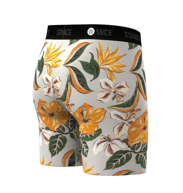 Et par Stance Kahuku Wholester herreboxershorts i lyseblå med et tropisk blomstermønster bestående af markante gule og orange blomster samt grønne blade på hvid baggrund. Disse boxershorts er fremstillet af det ultrabløde Butter Blend-materiale, der sikrer enestående komfort, og har en sort linning med teksten »STANCE« trykt i hvide bogstaver.