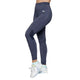 En person iført Kari Traa Julie High Waist Tight, Dame, Marin-høj talje og hurtigtørrende tights - og hvide sneakers med lyseblå og grønne detaljer - står på en almindelig hvid baggrund. Kun underkroppen og benene er synlige.