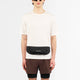 En person iført solbriller, en almindelig hvid t-shirt, brune shorts og Salomon Pulse Sling Belt (Unisex, sort) står på en almindelig hvid baggrund.