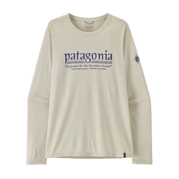 En langærmet Patagonia L/S Cap Cool Daily Shirt – Hut Tripper til kvinder i farven Dyno White, med rund hals og fremstillet af genanvendt polyester. Denne off-white løbetrøje har ordet »Patagonia« i blåt på forsiden, ledsaget af yderligere tekst nedenunder og et lille logo på venstre ærme. T-shirten er afbilledet lagt fladt ud på en hvid baggrund.