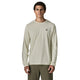 En mand står med ansigtet vendt fremad og har en lysbeige Patagonia L/S Cap Cool Daily Shirt – Hut Tripper, Herre, Dyno White – fremstillet af genbrugt polyester – samt olivengrønne bukser på. Hans arme hviler langs siden, og han har kort, krøllet hår. Baggrunden er ensfarvet hvid.