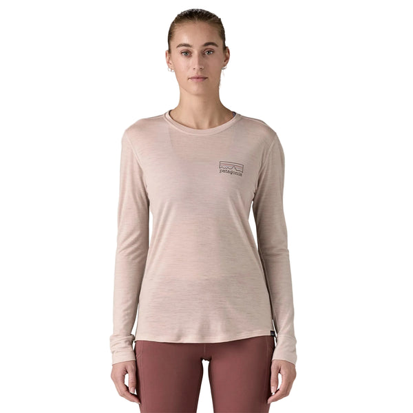 En person står og kigger fremad iført Patagonia W's L/S Cap Cool Merino Blend Graphic Shirt, Dame, Fitz Roy Strata/Shroom Taupe og lilla leggings på en almindelig hvid baggrund.