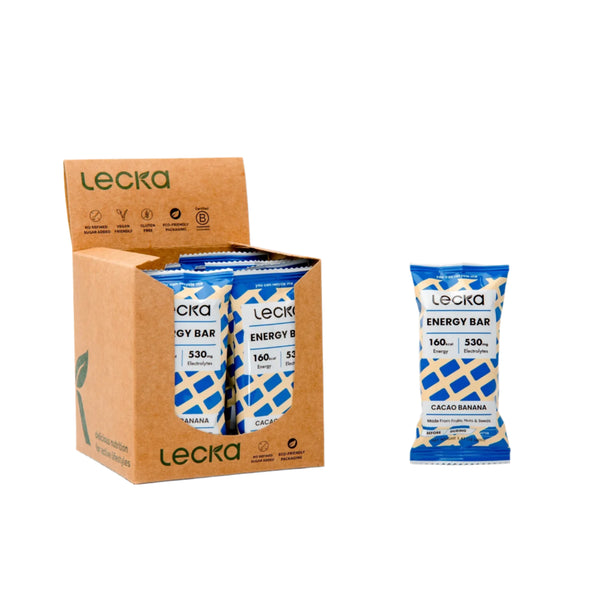 En papkasse mærket Lecka indeholder Energy Bar, Cacao Banana med plantebaserede ingredienser. En bar uden for kassen viser: Energy Bar, Cacao Banana, 160 kcal, 5,3 g protein og uden tilsat sukker.
