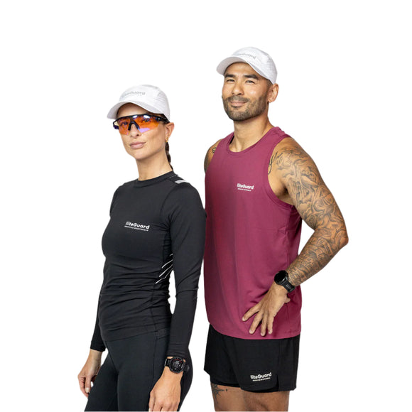 En kvinde i sort sportstøj og en mand i rødbrun ærmeløs top og shorts, begge iført Liiteguard Running Cap, Unisex, White og smartwatches, står side om side mod en hvid baggrund.