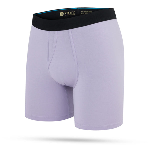 Et par Stance Lilac Wholester boxershorts til mænd i lyslilla med sort linning og Stance-logo i guld på hvid baggrund.