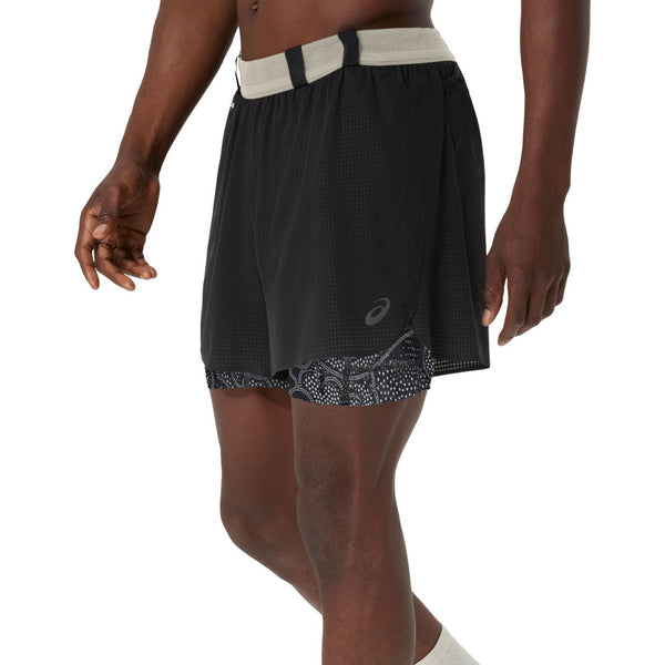 En person er iført ASICS Limited Series Metarun 4In 2-N-1 Short, Herre, i Performance Black/Cream. Kun underkroppen og overbenene er synlige mod en almindelig hvid baggrund.